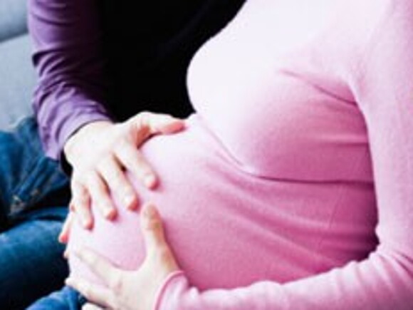 Une mère enceinte lit des conseils pour préparer l'arrivée de son bébé