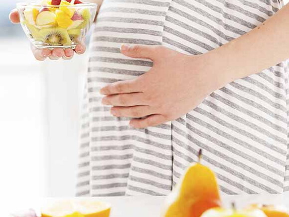 Femme enceinte tenant un bol de fruits - Gros Plan