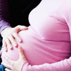 Une mère enceinte lit des conseils pour préparer l'arrivée de son bébé