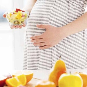 Maman enceinte tenant un bol de fruits pleins d'acide folique Maman enceinte tenant un bol de fruits pleins d'acide folique